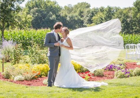 A bride and groom kissing in the grass.