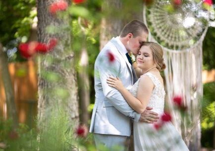 A man and woman hugging in front of trees.