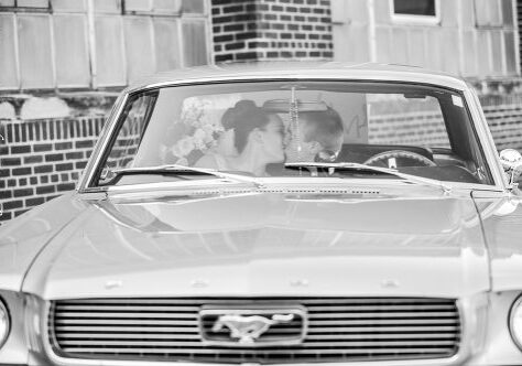 A couple kissing in the backseat of a car.