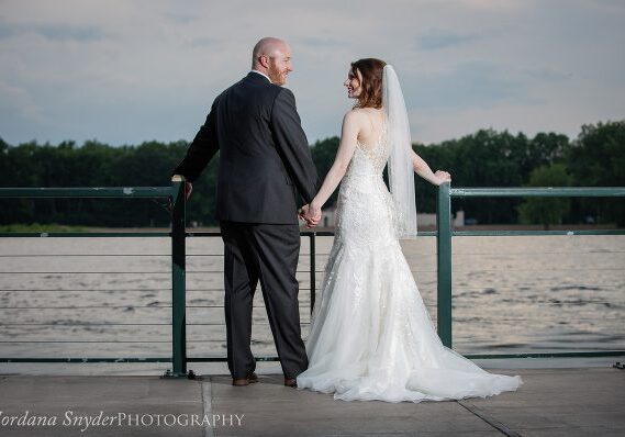 A man and woman holding hands on the side of a pier.