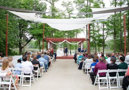 A wedding ceremony with many people sitting in chairs.