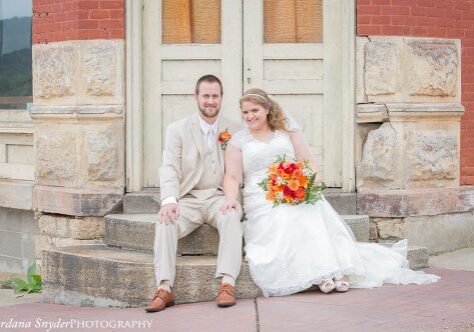 A bride and groom pose for a picture outside of the church.