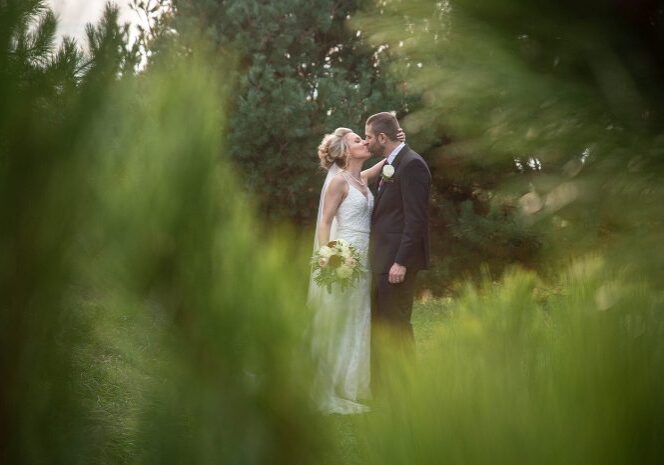 A bride and groom kissing in the middle of a field.