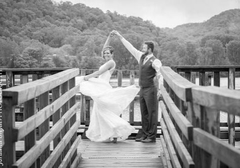A bride and groom are holding hands on the bridge.