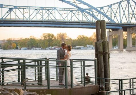 A couple is standing on the dock of a pier.
