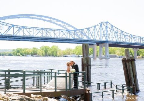 A bride and groom kissing on the pier.