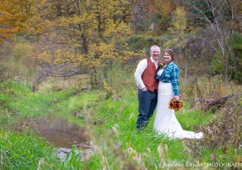 A man and woman standing in the grass near water.
