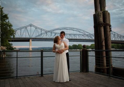 A man and woman kissing on the pier.
