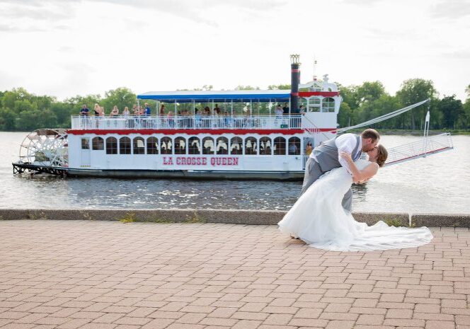 A bride and groom kissing in front of a boat.