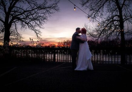 A couple is kissing in front of the sunset.
