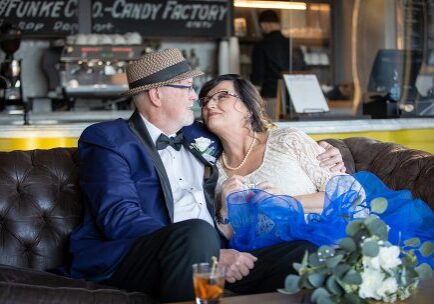 A man and woman sitting on top of a brown couch.