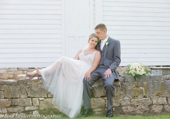 A man and woman sitting on the side of a wall.