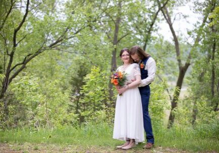 Two people standing in a field with trees