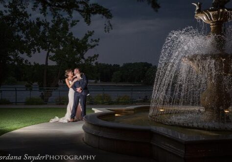 A couple is standing in front of a fountain