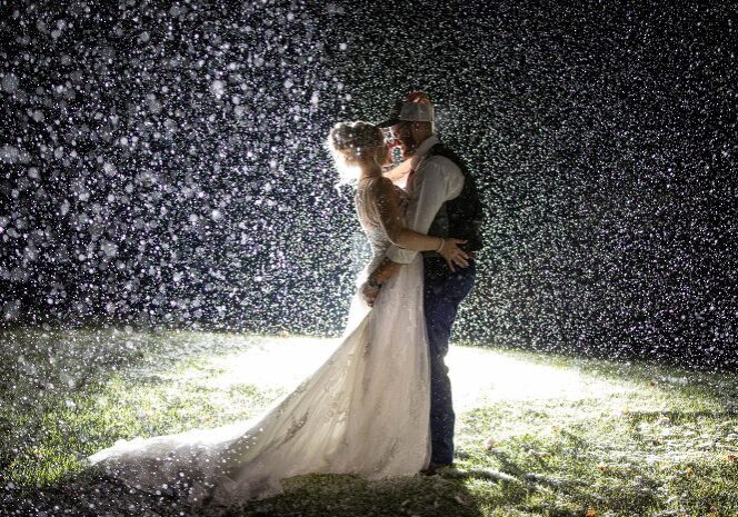 A bride and groom kissing in the rain.