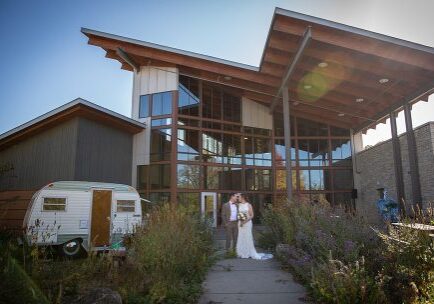 A bride and groom are standing outside of their wedding venue.