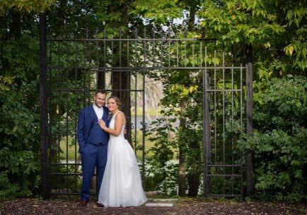 A man and woman posing for a picture in front of an iron gate.