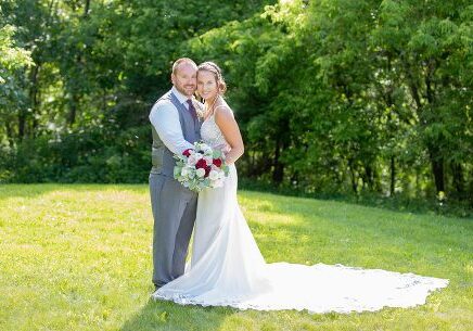 A man and woman posing for a picture in the grass.