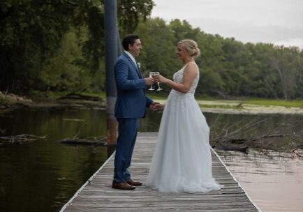 A man and woman standing on the dock of a lake.