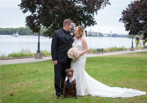 A bride and groom pose with their dog.