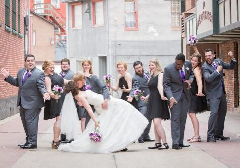 A bride and groom kissing in front of their wedding party.