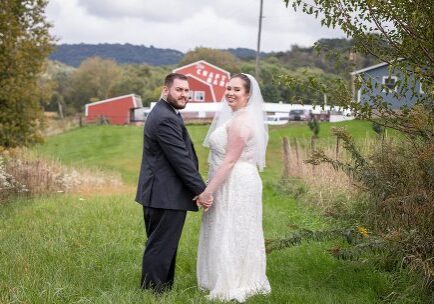 A newly married couple holding hands in the grass.