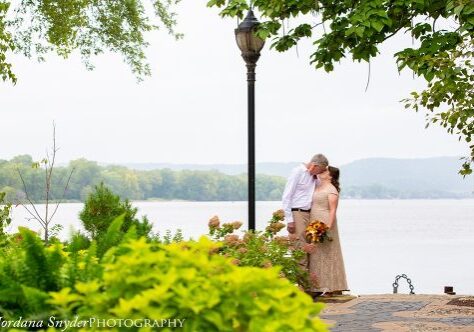 A man and woman kissing near the water.