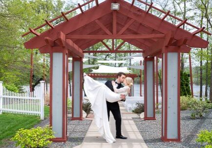 A man and woman kissing under an arbor.
