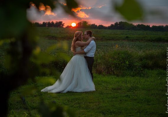 A bride and groom kissing in the sunset.
