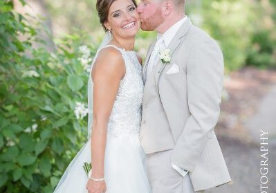 A bride and groom kissing on the side of a road.