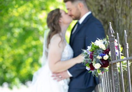 A bride and groom kissing in front of a tree.