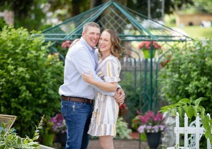 A man and woman hugging in front of a gazebo.