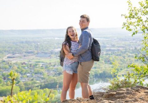 A man and woman standing on top of a hill.