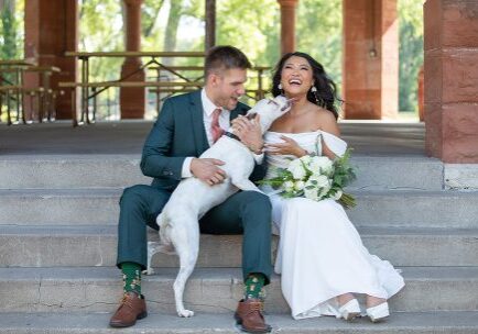 A man and woman sitting on steps with their dog.
