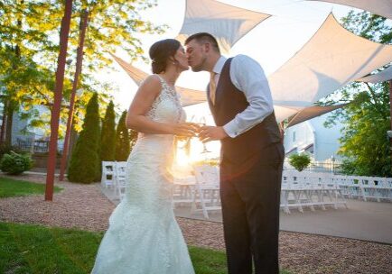 A bride and groom kissing under an umbrella.