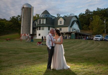 A man and woman standing in front of a barn.