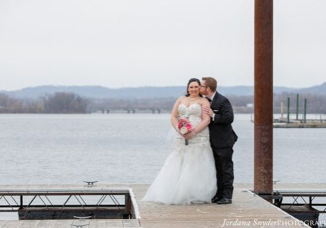 A bride and groom kissing on the pier.