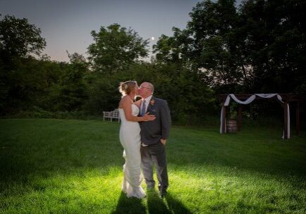 A bride and groom kissing in the grass.