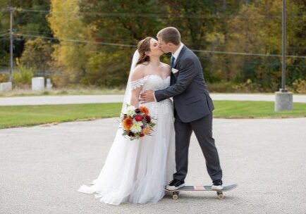 A bride and groom kissing on the side of a skateboard.