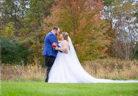 A bride and groom kissing in the grass.