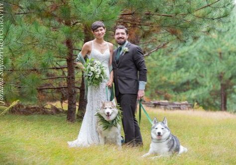A bride and groom pose with their dogs.