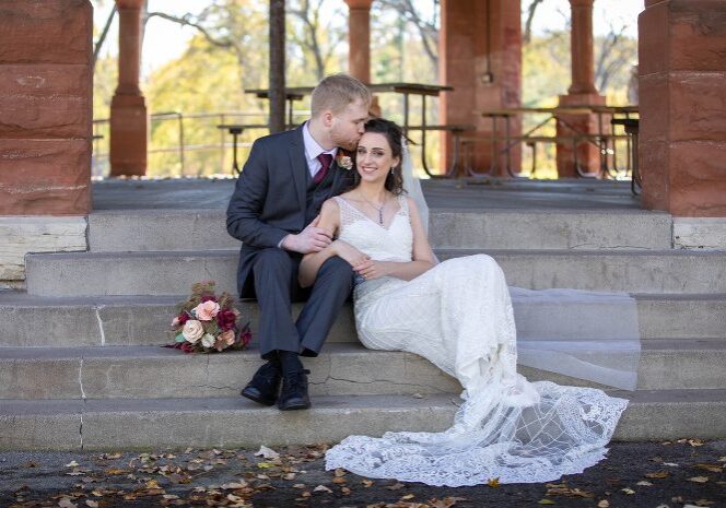 A man and woman sitting on steps in front of a gazebo.