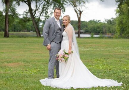 A man and woman posing for a picture in the grass.
