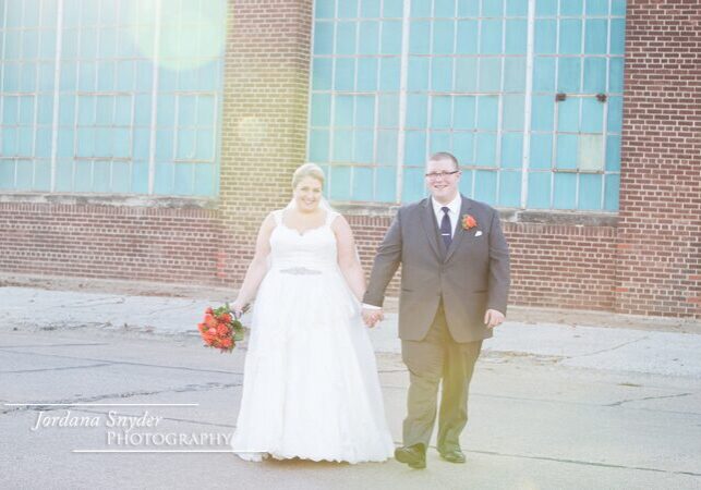 A man and woman holding hands in front of a building.