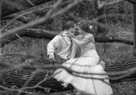 A man and woman kissing in front of some trees.