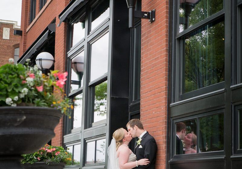 A bride and groom kissing in front of a building.